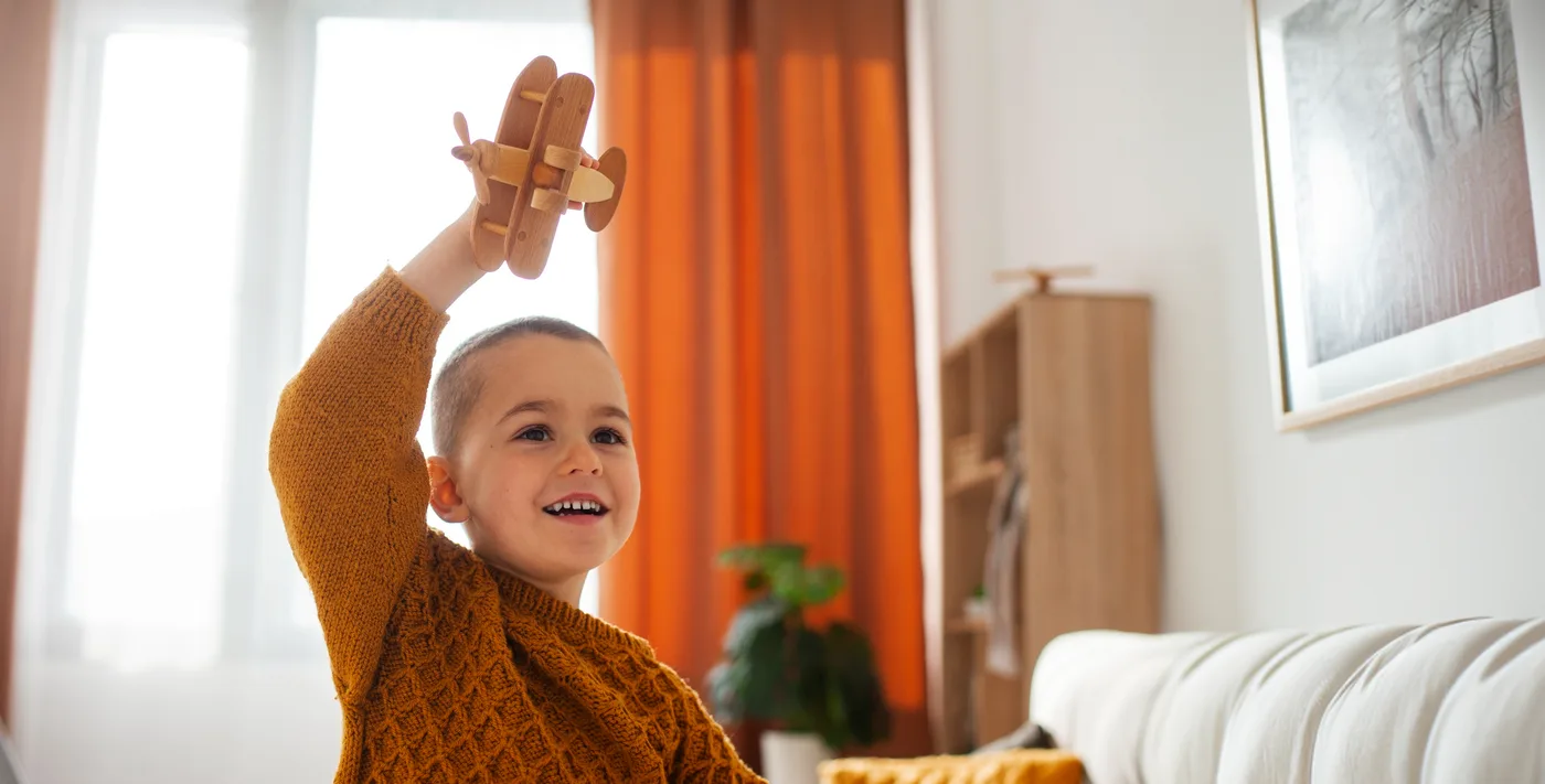Niño sonriendo con un avión de madera